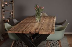 a wooden table with four chairs around it and flowers in a vase on the top