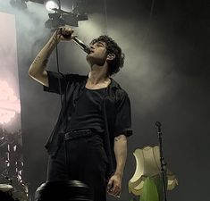 a man standing on top of a stage holding a microphone to his mouth and singing