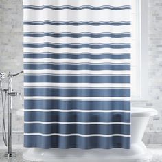 a blue and white striped shower curtain hanging in a bathroom with a tub next to it