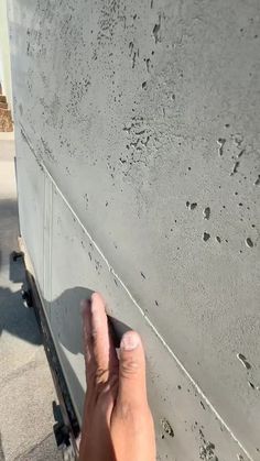 a hand is reaching up to the side of a concrete wall that has holes in it