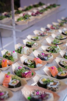 a table topped with lots of different types of sushi and other foods on trays