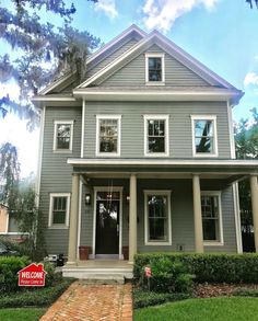 a gray house with a red sign in front of it