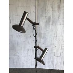 two black lamps on a metal pole against a white brick wall in an industrial style