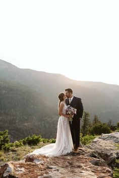 a bride and groom standing on top of a mountain