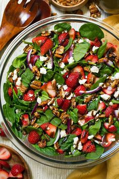 a salad with spinach, strawberries, nuts and feta cheese