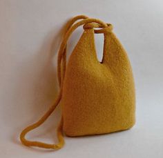 a small yellow purse sitting on top of a white table next to a brown cord