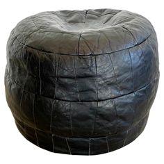 a large black leather poufce sitting on top of a white floor