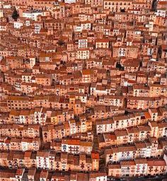 an aerial view of many buildings in a city with red roofs and brown roof tops