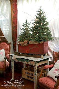 a small christmas tree in a wooden box on top of a table next to a window