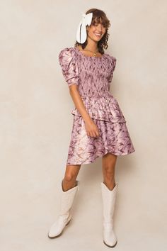 The Michelle Dress is the perfect mix of playful and chic. Made with a stunning purple floral knit fabric, this knee-length women's dress features a unique square neckline and 1/2 length fitted sleeves with a subtle puff at the cap. The asymmetrical tiered skirt adds a fun twist, while the hidden back zipper and smocked bodice provide a flattering fit. Maternity friendly too! Fitted Mini Dress With Square Neck In Purple, Purple Chic Mini Dress With Square Neck, Chic Purple Mini Dress With Square Neck, Chic Purple Square Neck Mini Dress, Purple Fitted Mini Dress With Puff Sleeves, Fitted Mauve Mini Dress With Ruffles, Fitted Purple Dress With Ruffle Hem, Fitted Purple Midi Dress With Short Sleeves, Purple Puff Sleeve Dress For Fall