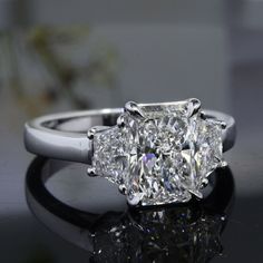 a three stone diamond ring on a reflective surface