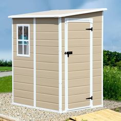 a small storage shed sitting on top of a gravel field next to a wooden platform