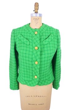 You'll be a sure fire hit in this bright 1960s suit jacket! This cheerful vintage suit jacket is a bright green color with contrasting darker green plaid and shiny gold buttons. Jacket is lined. LABEL: - FABRIC: feels like wool/wool blend SHOULDERS: 15" BUST: 40"  WAIST: 37" measured below 3rd button SLEEVE LENGTH: 15" measured underarm to end of sleeve LENGTH: 18.5" CONDITION: great, has small hole on back right sleeve(see photo) PINNED TO MODEL?: no ☝For reference Mona's measurements are S 12. Retro Green Blazer For Workwear, Retro Green Blazer For Work, Fitted Green Tweed Jacket With Button Closure, Retro Green Formal Outerwear, Retro Green Blazer For Spring, Fitted Green Retro Outerwear, Green Tweed Jacket With Buttons For Work, Green Fitted Retro Outerwear, Vintage Green Single Breasted Blazer