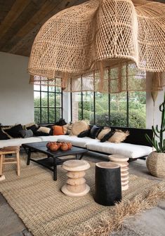 a living room filled with lots of furniture next to a large bamboo umbrella hanging from the ceiling