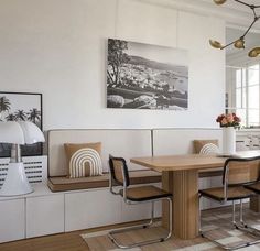 a dining room table with four chairs and a bench in front of the wall that has pictures on it