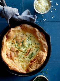 a baked dish in a cast iron skillet on a blue table with silverware