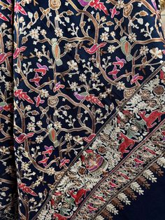 an intricately designed blue shawl with red, white and pink flowers on it