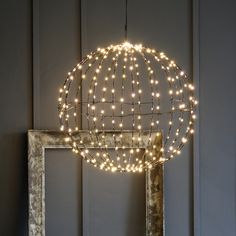 a light fixture hanging from the ceiling in front of a mirror with lights on it