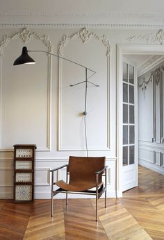 an empty room with a chair, lamp and other items on the wooden flooring