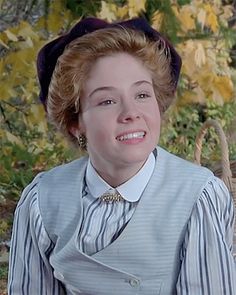 a woman wearing a blue and white striped shirt with a black hat on her head