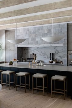 a kitchen with an island and stools in the center, along with several lights hanging from the ceiling