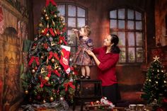 a woman and her daughter decorating a christmas tree