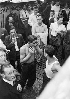 an old black and white photo of a man covering his face in front of a crowd