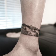 a man's foot with a wave tattoo on it