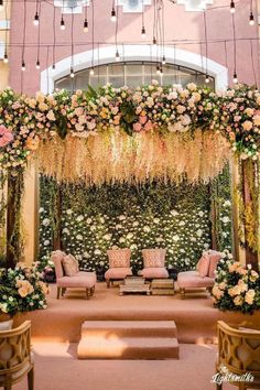 an outdoor ceremony setup with flowers and greenery on the wall, couches and chairs