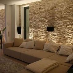 a living room filled with lots of furniture and walls covered in stone tiles on the wall