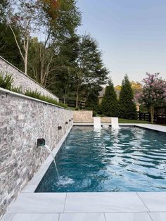 an outdoor swimming pool surrounded by stone walls