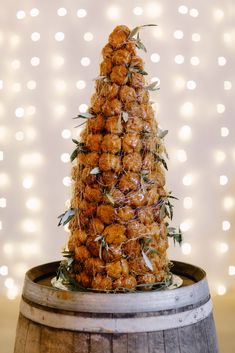 a pineapple sitting on top of a wooden barrel next to a string of lights