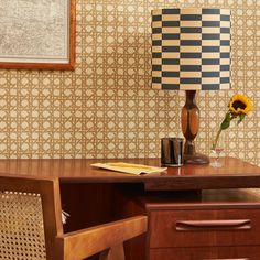 a wooden desk topped with a lamp next to a vase filled with sunflowers