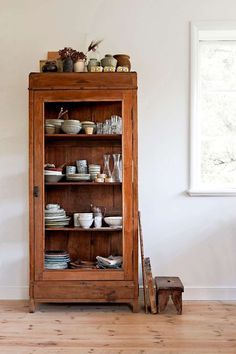 an old wooden cabinet with dishes on it