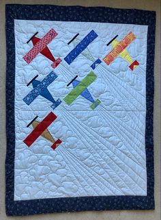 a quilted wall hanging with small airplanes on it