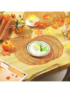 a wooden table topped with plates covered in fall leaves