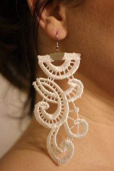 a close up of a woman's neck wearing earrings with intricate designs on it