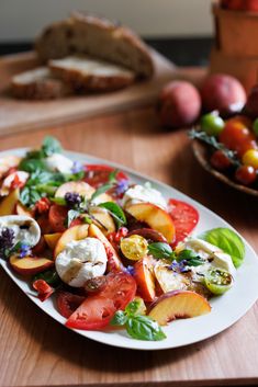 a white plate topped with lots of fruit and veggies on top of a wooden table