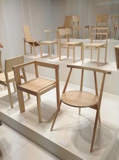 several wooden chairs on display in a room