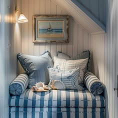 a blue and white couch sitting under a window next to a framed painting on the wall