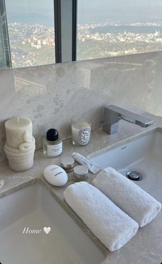 a white sink sitting under a bathroom mirror next to a window with city view in the background