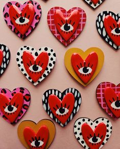 many heart shaped cookies are arranged on a pink surface with black and white polka dots