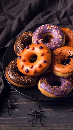 a plate full of doughnuts with sprinkles on them and spider decorations