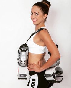 a woman holding a pair of skis in her right hand while standing next to a white wall