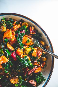 a bowl filled with vegetables and meat on top of a white countertop next to a fork