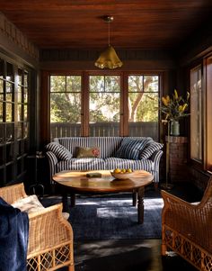 a living room with wicker furniture and large windows