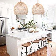 a kitchen with three stools in front of an island and four lights hanging from the ceiling