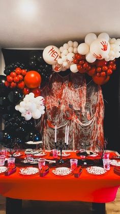 the table is set up with red and white balloons, silverware, and plates