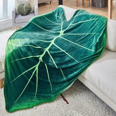 a living room filled with furniture covered in a green leafy blanket on top of a white couch