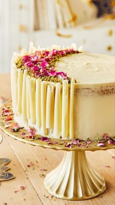 a cake with white frosting and pink flowers on the top is sitting on a table